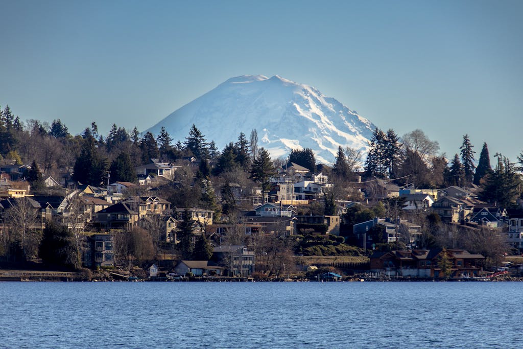 Scenic view of Mount Rainier with residential suburb along the water on a clear day.